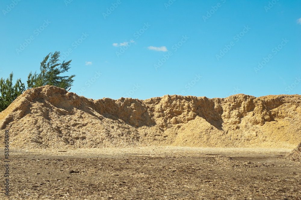 a product of wood processing, in the photo mountains of wood chips and sawdust against a blue sky