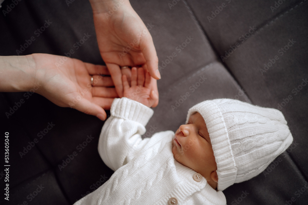 the newborn sleeps, the mother and father hold the newborn's hand