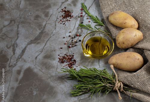 Raw potatoes, rosemary, olive oil, colorful peppers and dried tomatoes are the ingredients for delicious baked potatoes. Natural background with a space for text