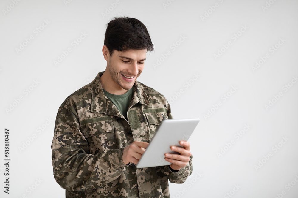Cheerful guy soldier using modern digital tablet Cheerful guy soldier using modern digital tablet