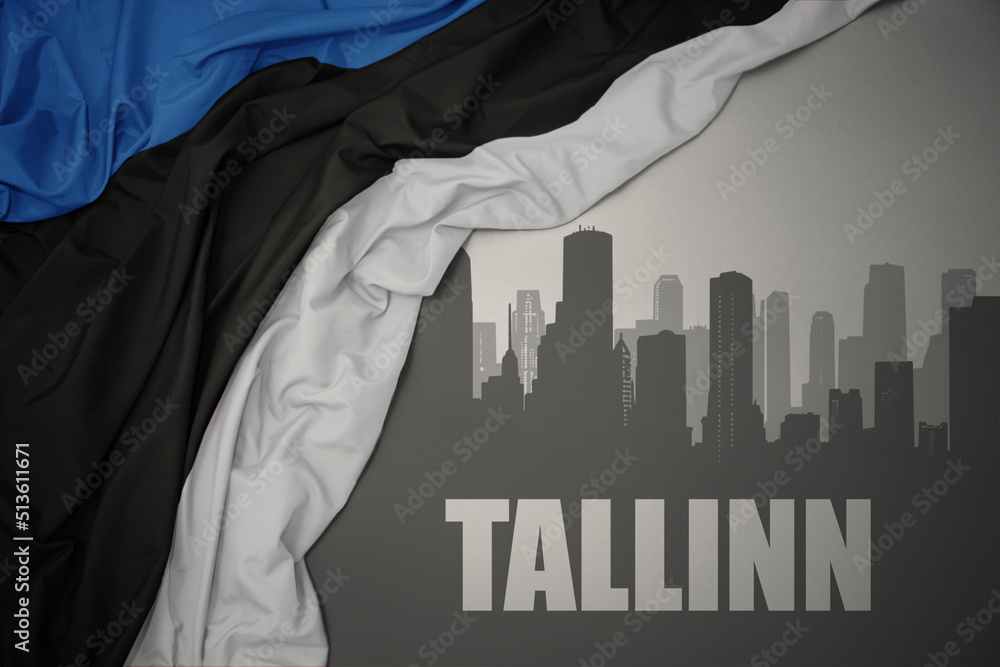 abstract silhouette of the city with text Tallinn near waving national flag of estonia on a gray background.