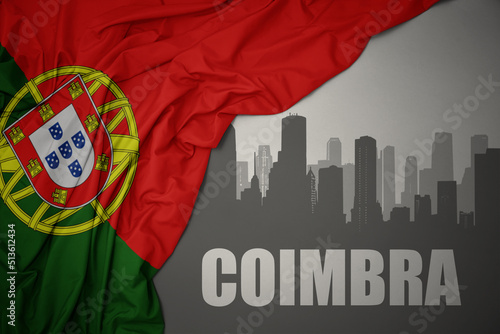 abstract silhouette of the city with text Coimbra near waving national flag of portugal on a gray background.