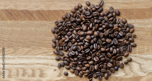 Large grains of roasted coffee lie on a wooden background