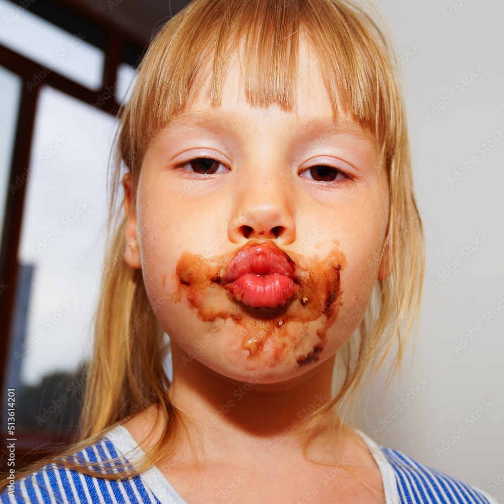 Little girl with a dirty mouth is eating Alpine chocolate. Lips with a bow. Little girl with a dirty mouth is eating Alpine chocolate. Lips with a bow.