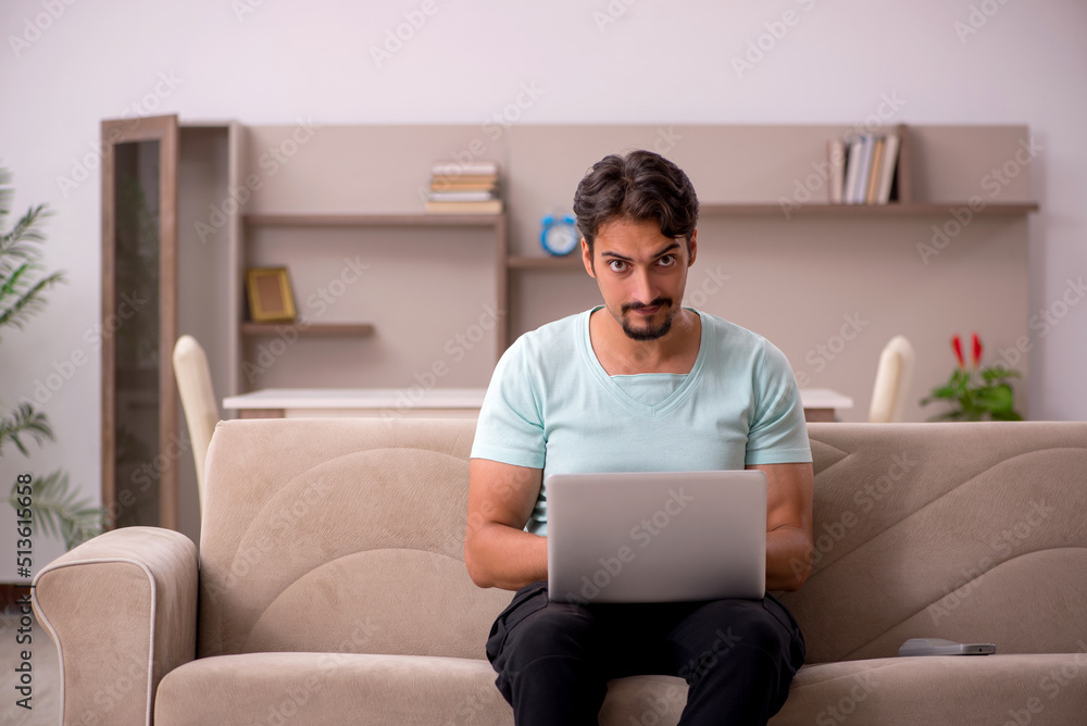 Young man sitting on the sofa with computer at home Young man sitting on the sofa with computer at home