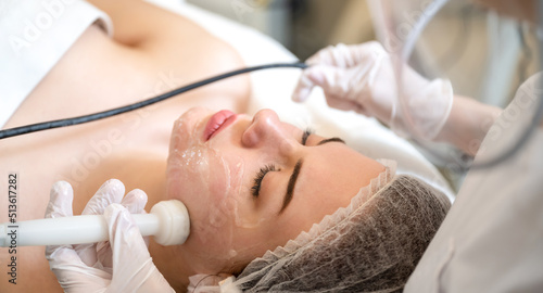 Fotografija High angle view close up of beautician applying Radio frequency skin tightening treatment on woman's face using a medical equipment in beauty salon