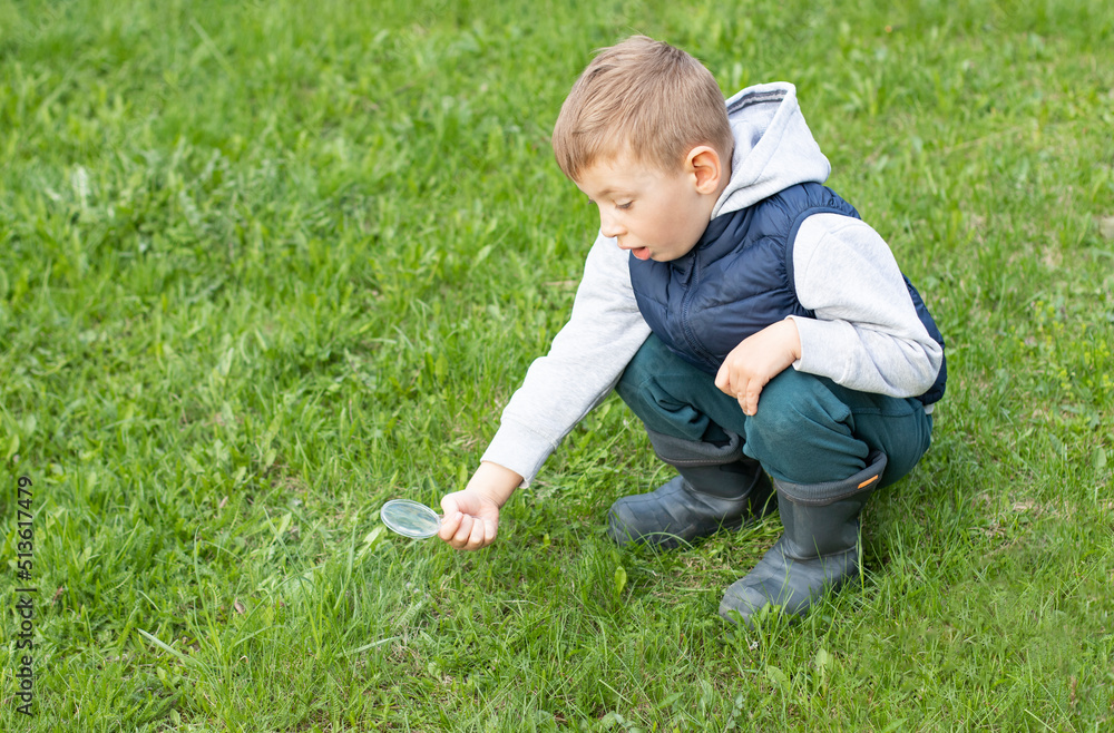 A little boy with a magnifying glass is studying the world around him A little boy with a magnifying glass is studying the world around him