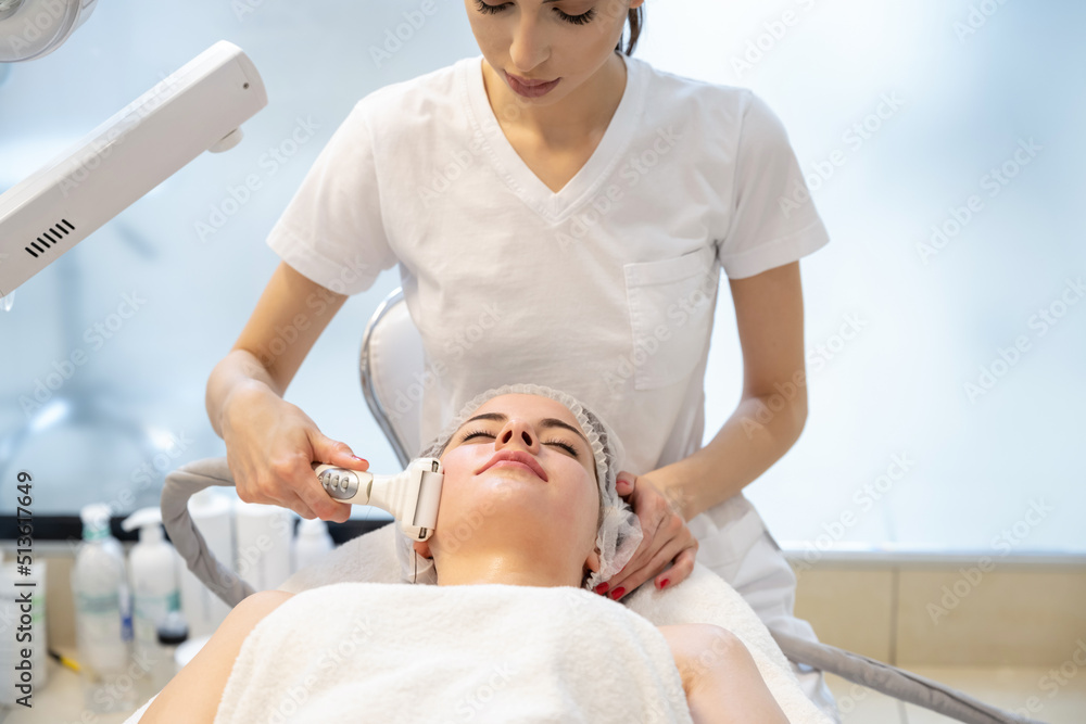 Young woman enjoying lifting and rejuvenating procedure in beauty salon.