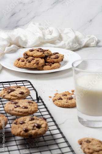 Cookies with chocolate chip on a plate. Milk on the side. Selective focus.