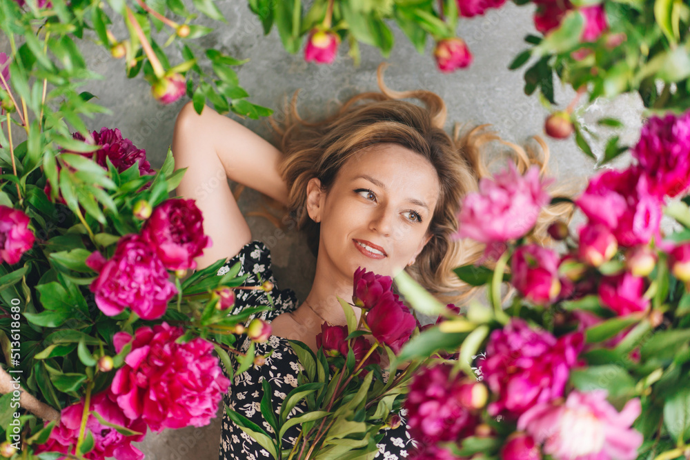 an attractive middle-aged blonde woman lies in flowers on the gray floor. an attractive middle-aged blonde woman lies in flowers on the gray floor.