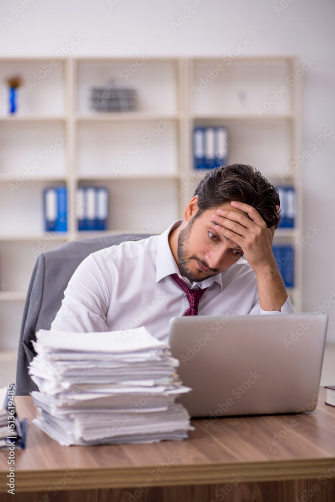 Naklejka premium Young male employee and too much work in the office