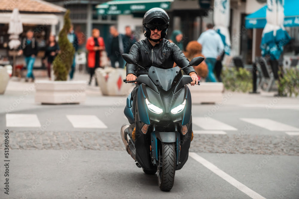 A modern motorcyclist drives on a motorcycle on the road in the city.