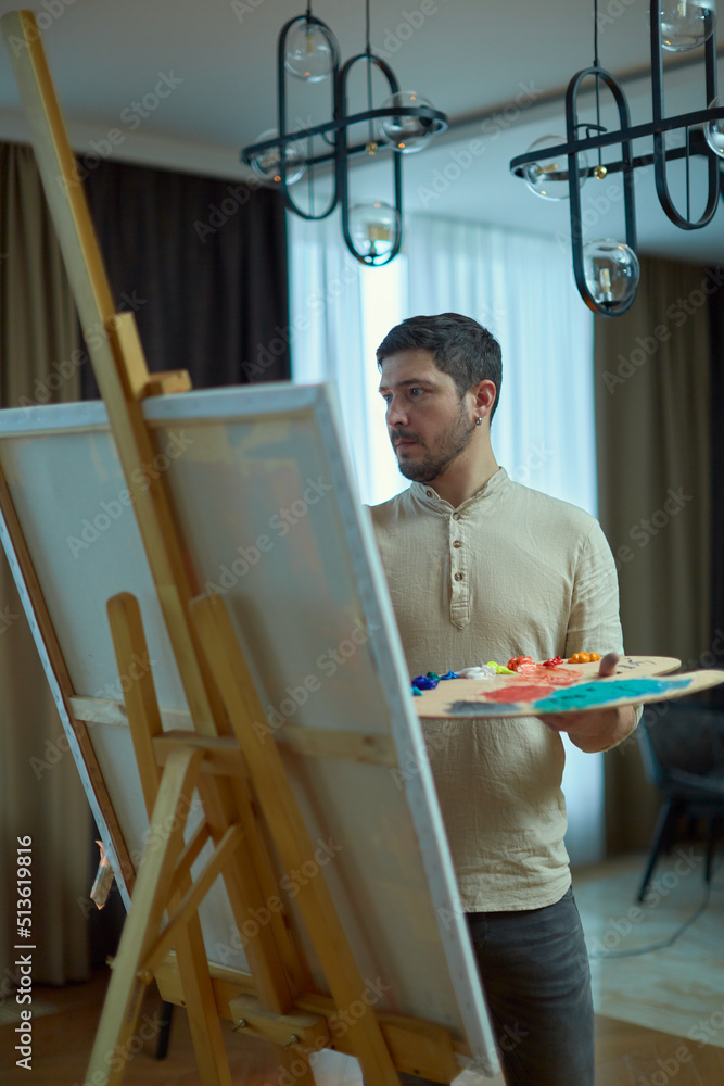 Modern artist at work. Focused male painter create painting on canvas near easel. Contemporary art, creative leisure
