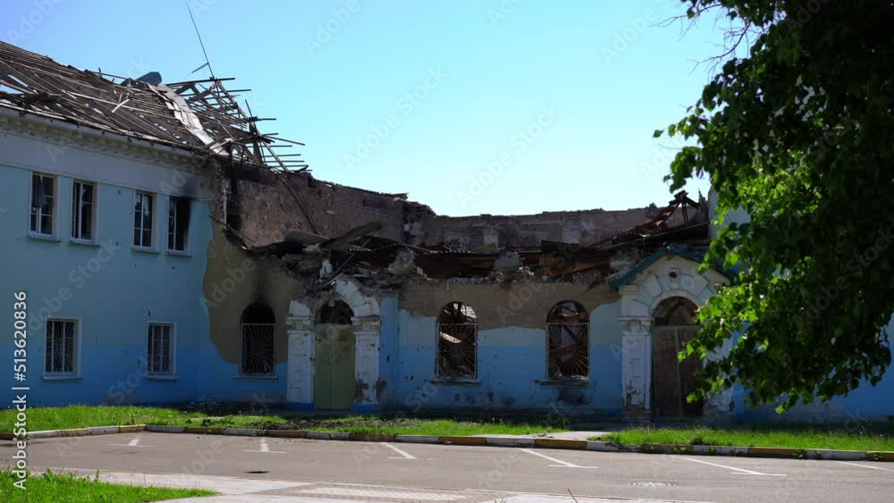 Wide shot blue building bombed in Kyiv suburbs in Ukraine with no roof. Destroyed ruined house outdoors on sunny day. War and bombing consequences