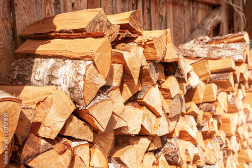 Chopped firewood stacked in a woodpile, for kindling a stove or fireplace, for heating a house. Concept of economic fuel crisis.