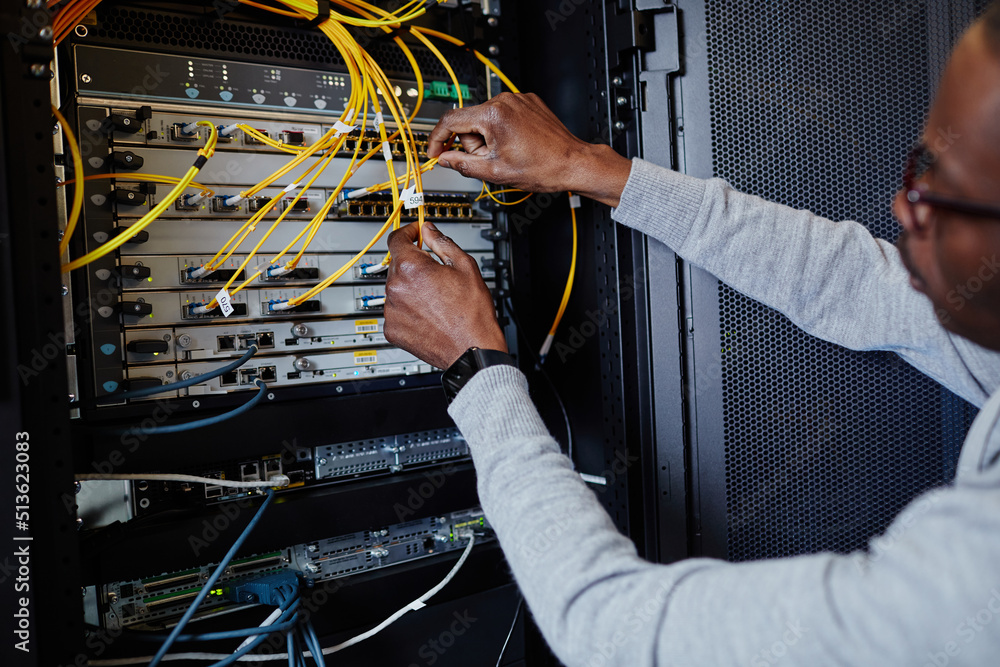 Close up of IT engineer connecting cables in server room while setting up data network, copy space Close up of IT engineer connecting cables in server room while setting up data network, copy space