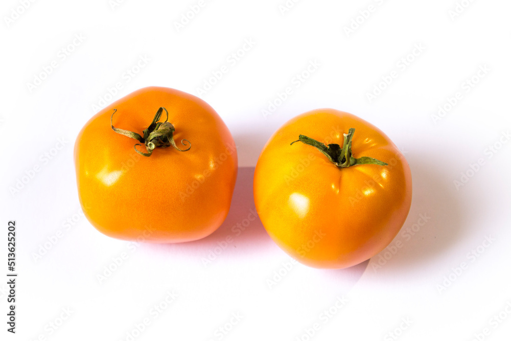 two yellow tomatoes lie on a white background two yellow tomatoes lie on a white background
