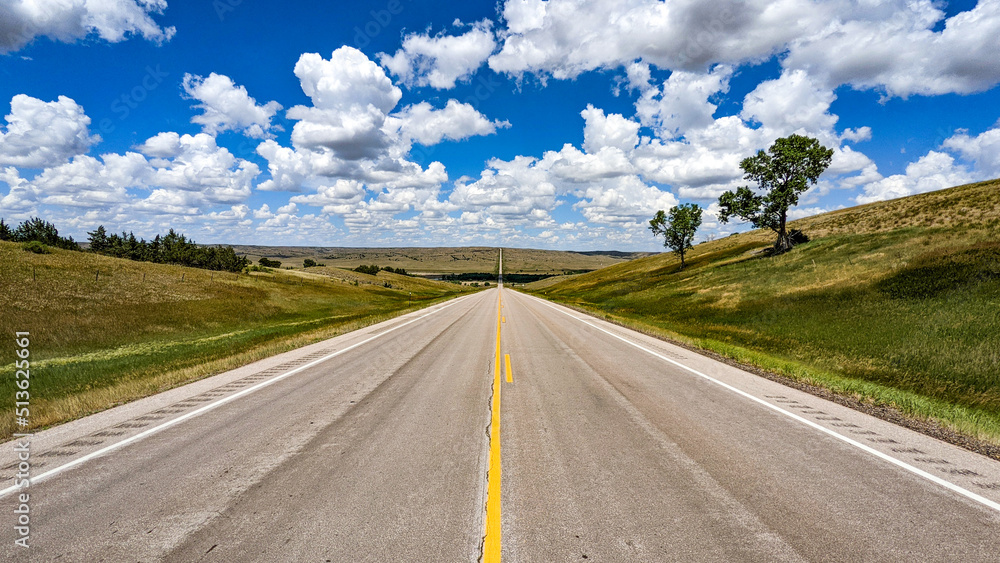 A road stretches to the horizon. Above is a sea of little fluffy clouds. Route 73 in South Dakota.