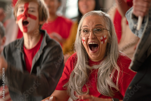 Fotografia Excited senior woman football fan supproting English national team in live soccer match at stadium