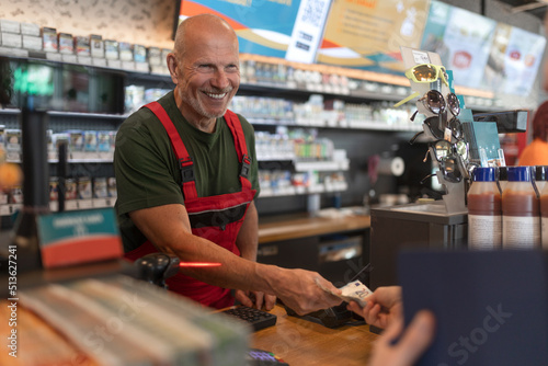 Foto Employee taking cash payment from costumer in gas station, close-up