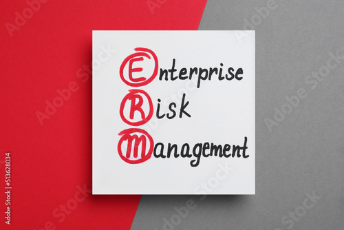 Paper with ERM abbreviation and its interpretation (Enterprise Risk Management) on color background, top view photo