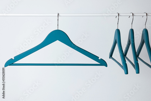 Blue clothes hangers on metal rail against light background