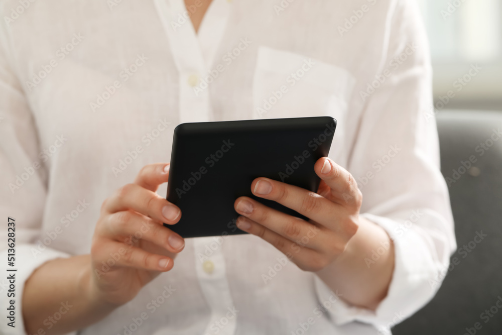 Young woman using e-book reader at home, closeup Young woman using e-book reader at home, closeup