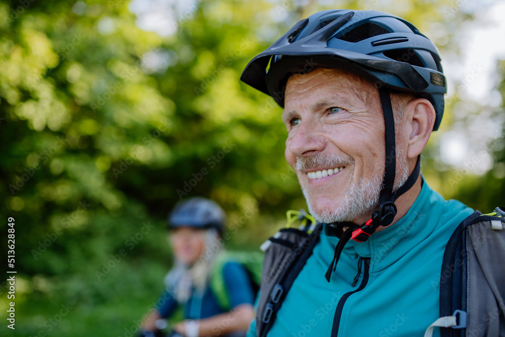 Active senior couple riding bicycles at summer park, man with bicycle helmet, healthy lifestyle concept. Active senior couple riding bicycles at summer park, man with bicycle helmet, healthy lifestyle concept.