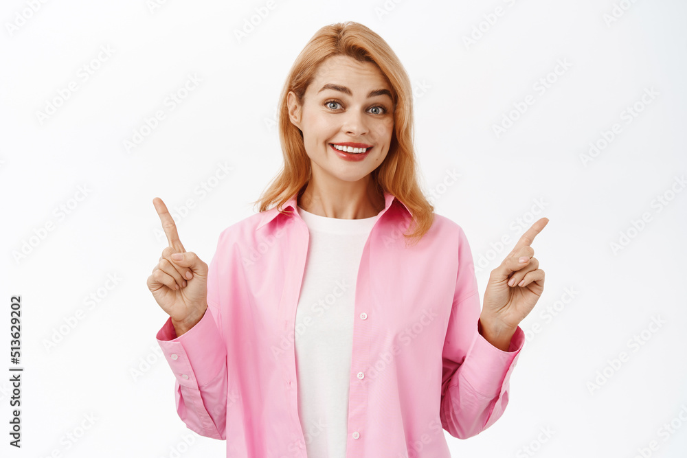 Portrait of cute smiling woman pointing sideways, showing two ways, left and right side banner, standing over white background Portrait of cute smiling woman pointing sideways, showing two ways, left and right side banner, standing over white background