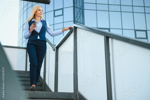 Beautiful Woman Going To Work With Coffee Walking Near Office Building. Portrait Of Successful Business Woman Holding Cup Of Hot Drink.