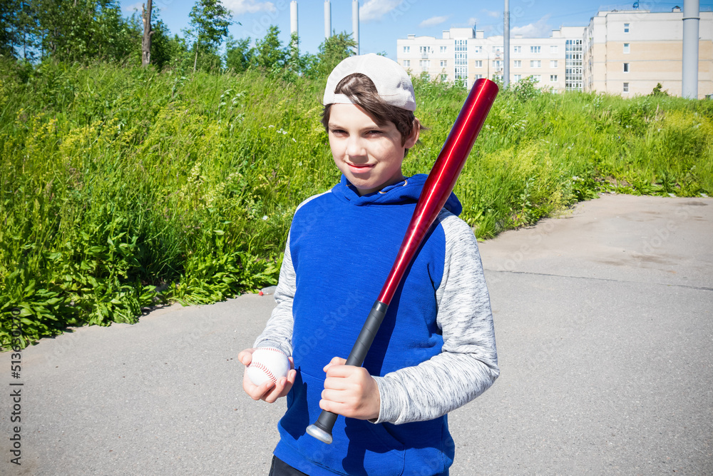 Smiling boy with baseball bat and ball against green grass outdoors on sunny day Smiling boy with baseball bat and ball against green grass outdoors on sunny day