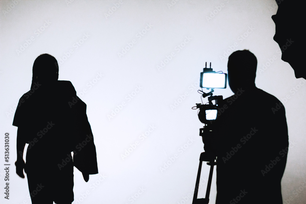 Backstage of video clip recording and audiovisual production in photographic studio white background, mans silhouette