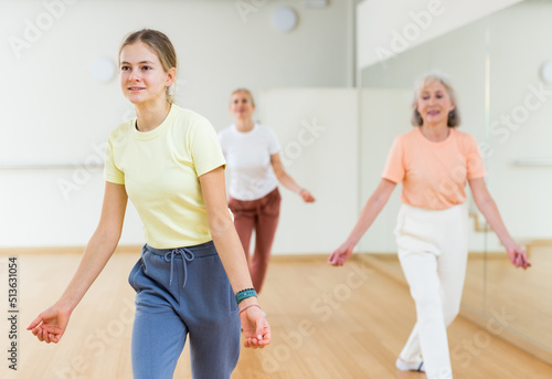 Teenage girl dancing jazz style dance during group training in studio.
