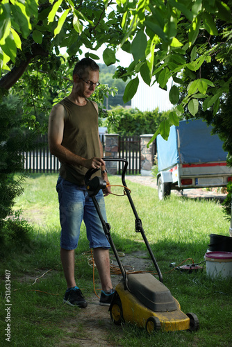 mowing the grass with an electric mower by a person