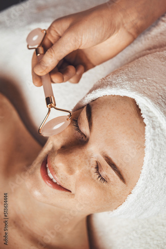Cuadro en lienzo Patient receiving anti-aging face massage with jade roller face massager at spa salon