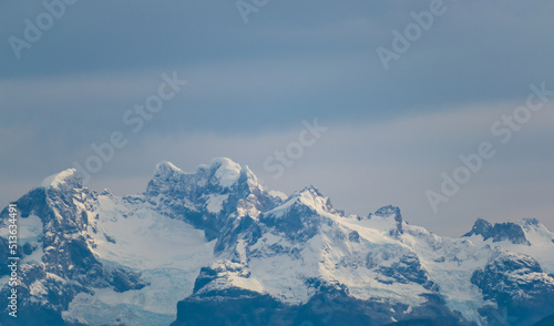 Picos de montañas nevadas rodeadas de nubes de colores azul opaco, nubes nimbostrato photo