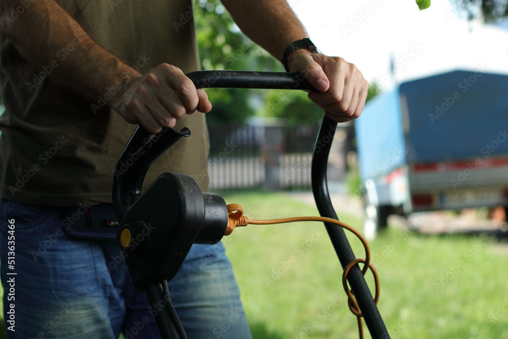 mowing the grass with an electric mower by a person mowing the grass with an electric mower by a person