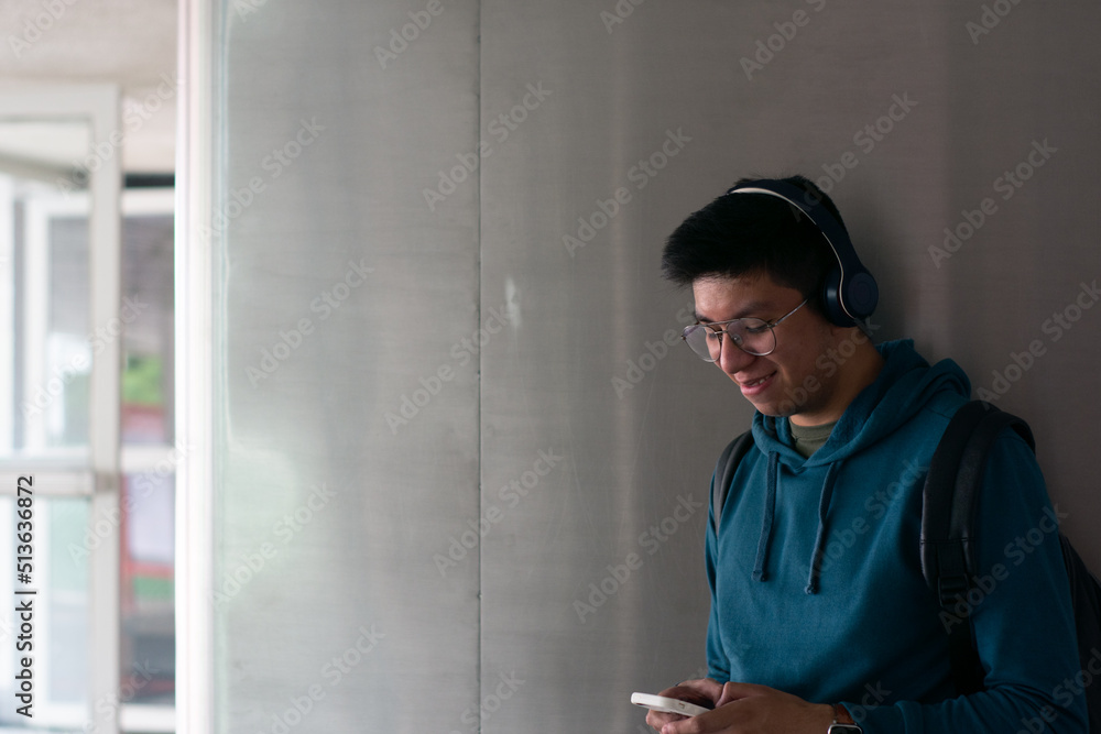 young man types on his cellphone while is listening to music and copy space 