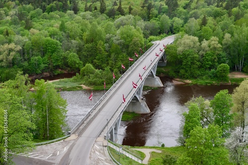 Aerial photo of a bridge decorated with many Latvian flags over Gauja river in Sigulda, Latvia. Empty