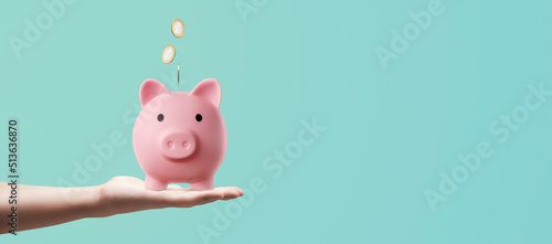 man holding a pink piggy bank with his hand and depositing coins - savings concept photo