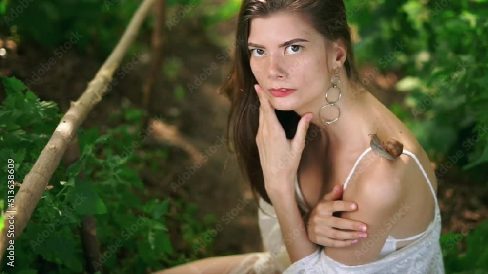 young white thin girl of model appearance with long hair with a snail on her shoulder against the backdrop of nature in summer young white thin girl of model appearance with long hair with a snail on her shoulder against the backdrop of nature in summer