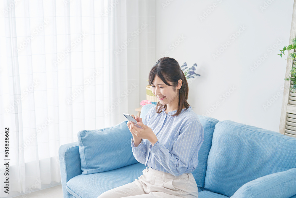 リビングでスマホで使う女性 リビングでスマホで使う女性