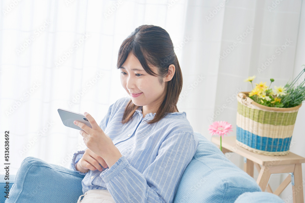 リビングでスマホで動画を見る女性