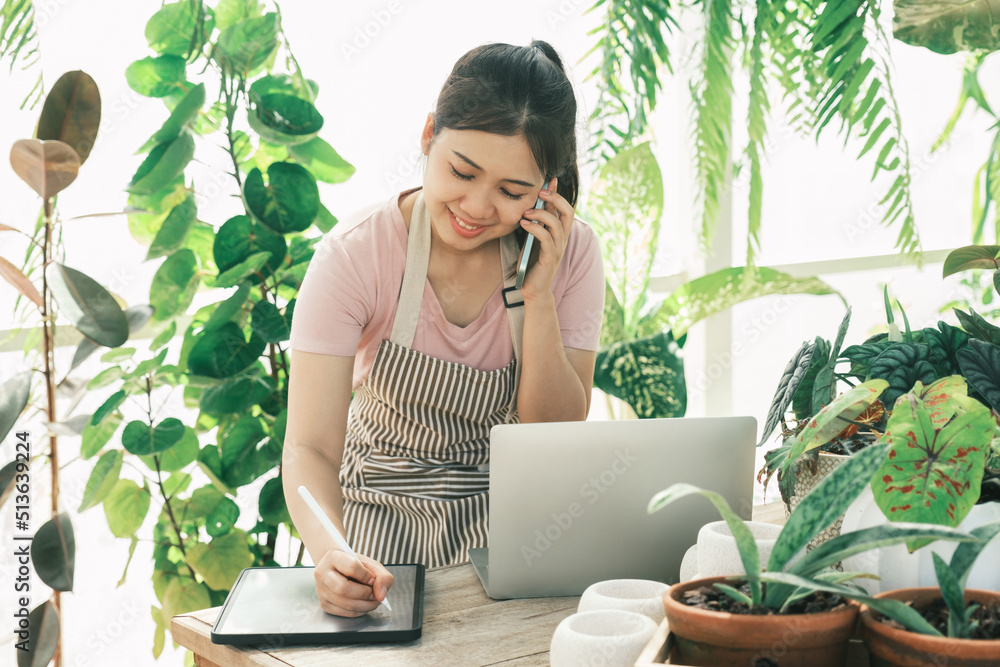 Young woman gardener is standing in the garden to contact customers. Young woman gardener is standing in the garden to contact customers.