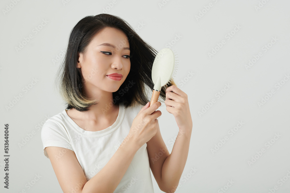 Portrait of smiling young woman with fresh haircut brushing hair with plastic brush Portrait of smiling young woman with fresh haircut brushing hair with plastic brush