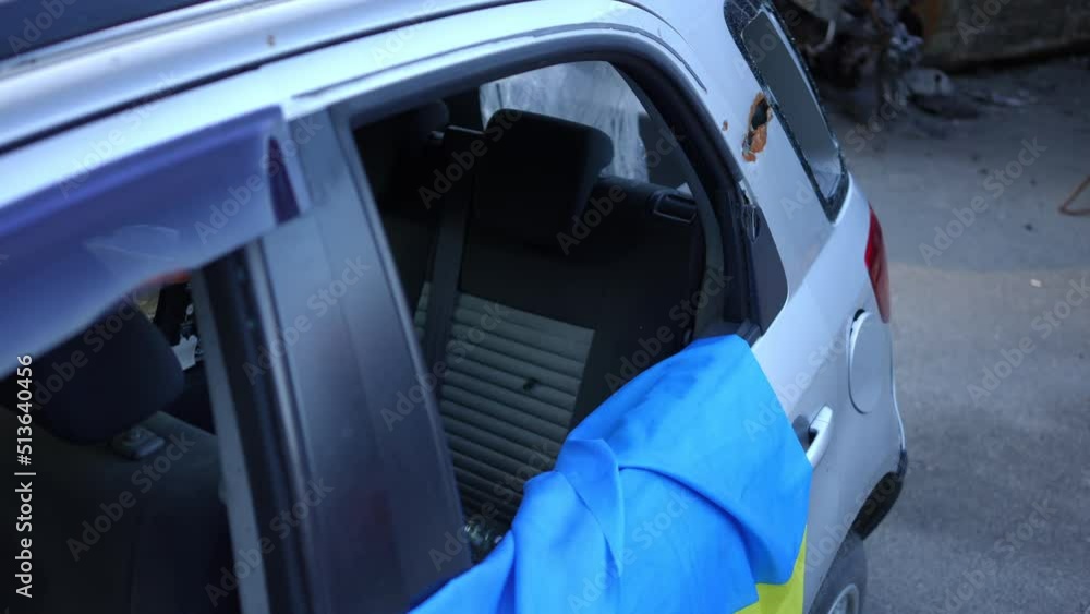 Closeup ruined abandoned car with bullet holes and Ukrainian flag