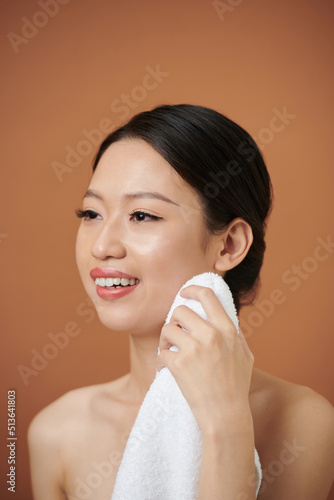 Asian young woman wiping face and body with soft white towel