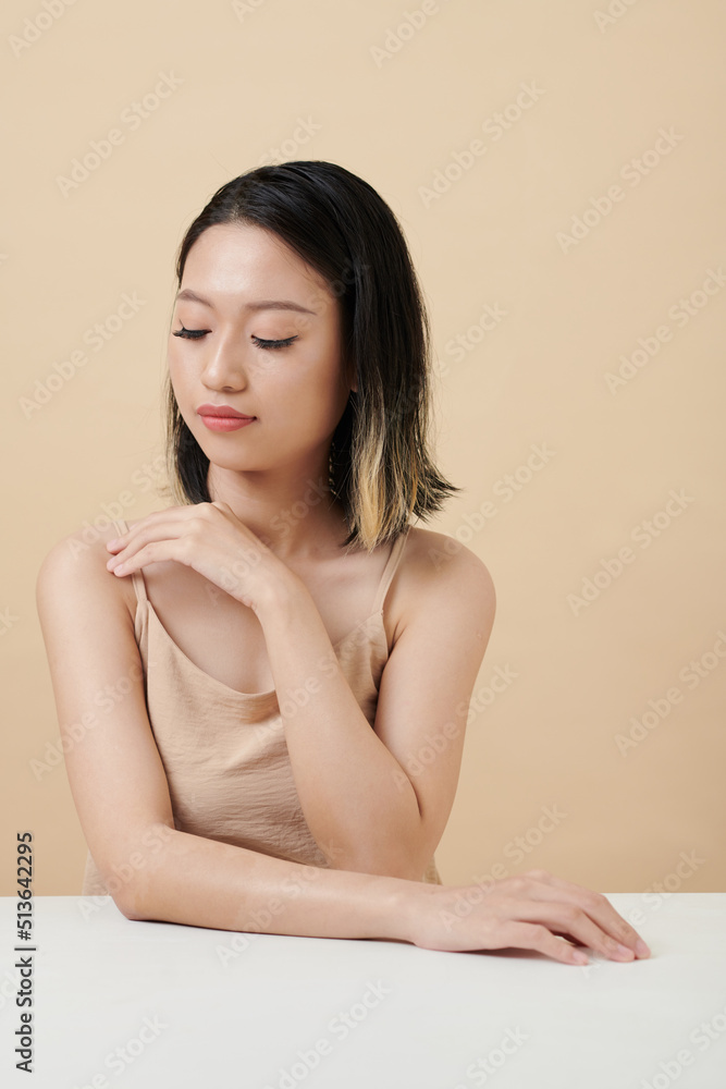 Young Asian woman touching strap of her silk top Young Asian woman touching strap of her silk top