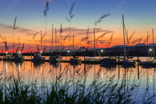 Large yacht harbor in orange sunset light, luxury summer cruise, sailboats in summer sunset. © Elena_Alex