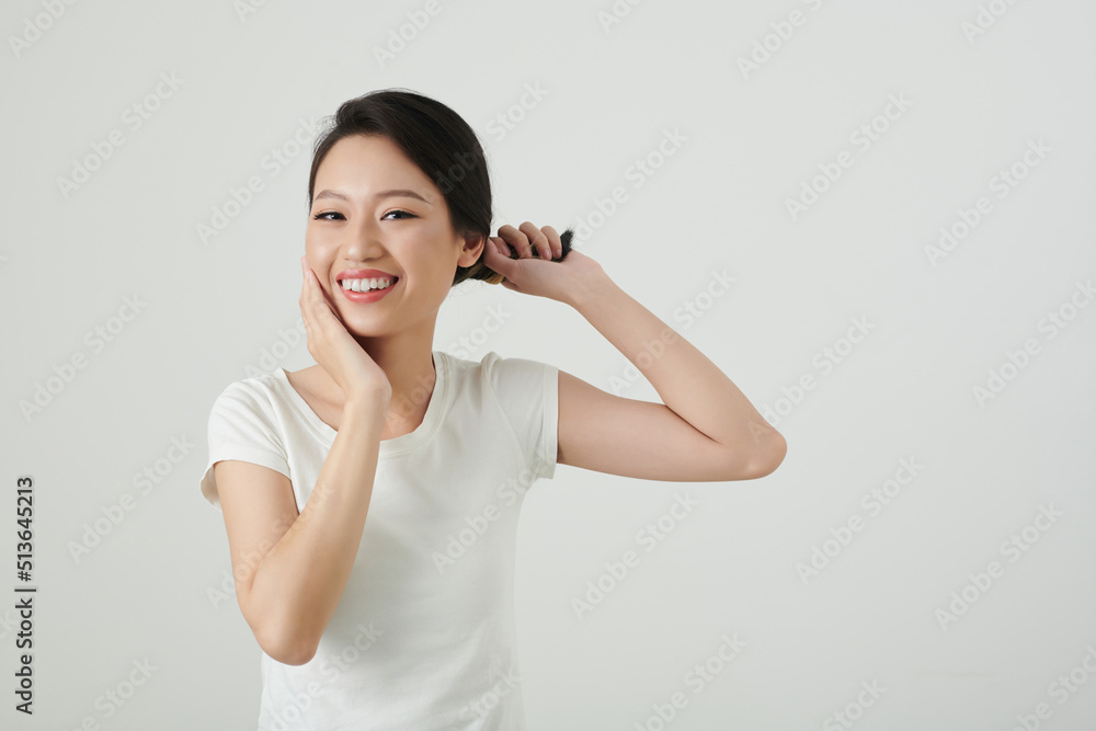 Portrait of young Asian woman twisting hair and touching her face Portrait of young Asian woman twisting hair and touching her face